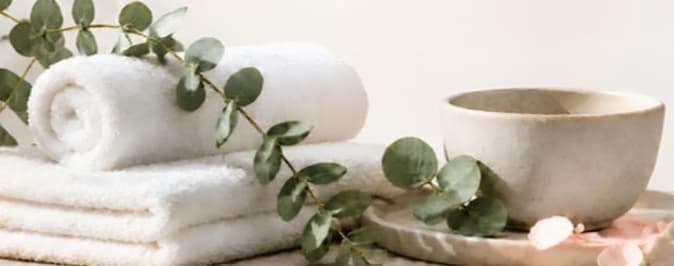 Rolled spa towels, eucalyptus, and a ceramic bowl